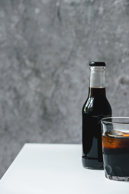 cold brew coffee with ice in glass and bottle on white table
