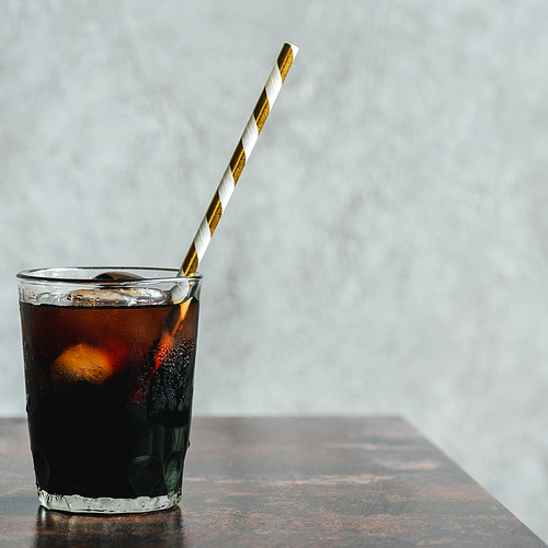 cold brew coffee with ice and  straw in glass on wooden table