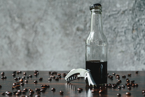 cold brew coffee in bottle near opener and coffee beans