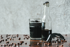 cold brew coffee in bottle and glass near opener and coffee beans