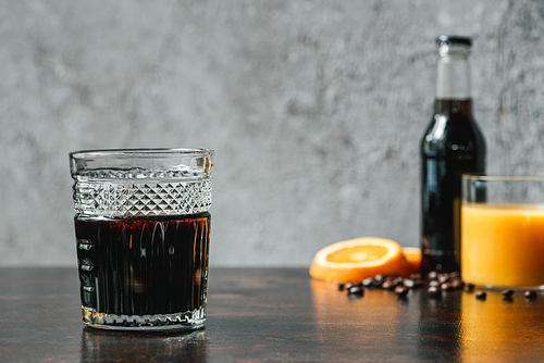 selective focus of cold brew coffee near bottle, orange juice and coffee beans