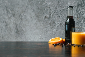 selective focus of cold brew coffee in bottle near orange juice and coffee beans