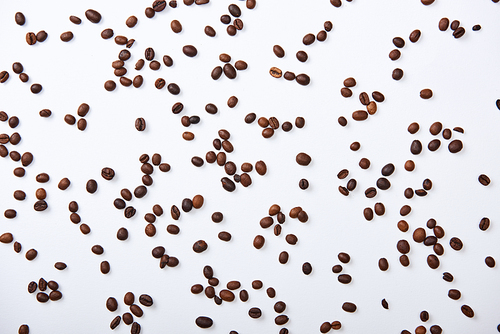 top view of coffee beans scattered on white background
