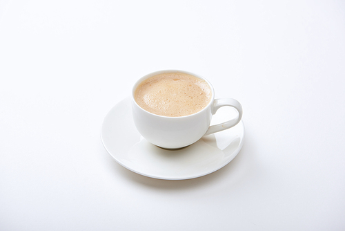 delicious coffee with foam in cup on saucer on white background