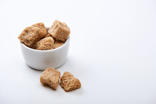 granulated brown sugar in bowl on white background with copy space
