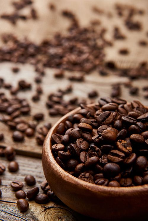 close up view of fresh roasted coffee beans in bowl on wooden board