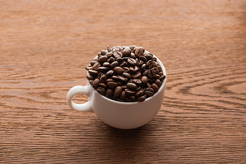 cup of fresh roasted coffee beans on wooden table