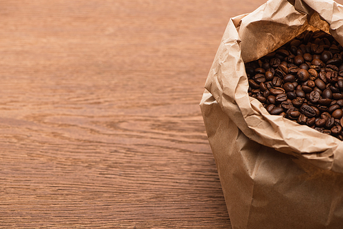fresh roasted coffee beans in paper bag on wooden table