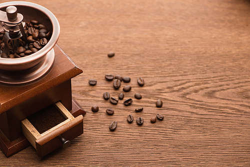 fresh roasted coffee beans near coffee grinder on wooden table