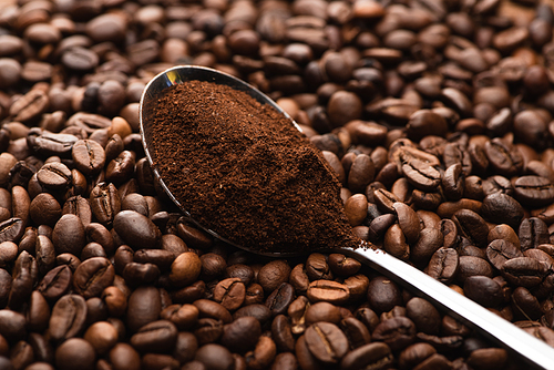 selective focus of fresh roasted coffee beans and ground coffee in spoon
