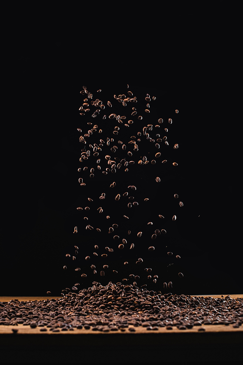 roasted coffee beans in pile and in air isolated on black