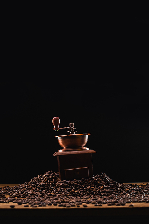 coffee grinder on fresh roasted coffee beans isolated on black