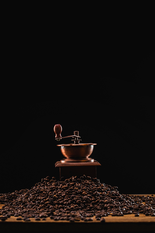 coffee grinder on fresh roasted coffee beans isolated on black