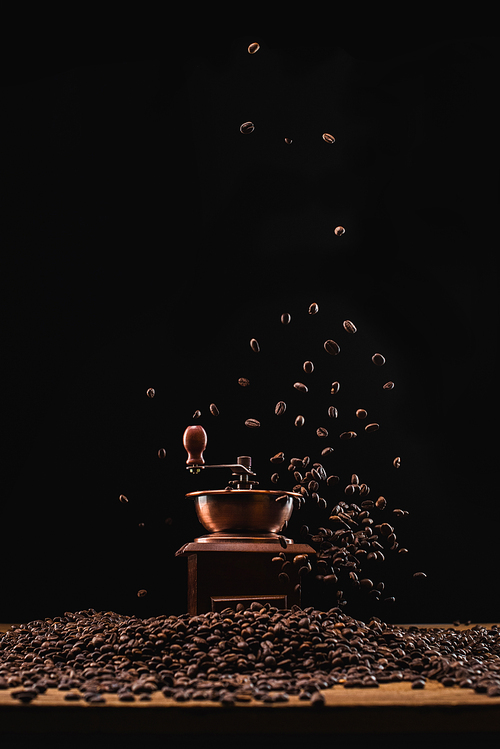 coffee grinder and fresh roasted coffee beans in air isolated on black