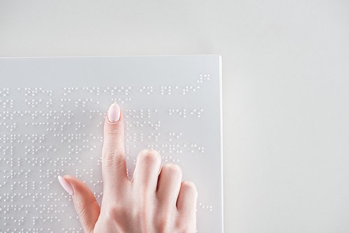 top view of young woman reading braille text on white paper with copy space