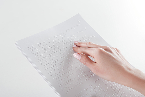 cropped view of young woman reading braille text with hand on white paper