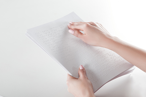 cropped view of young woman reading braille text with hand on white paper