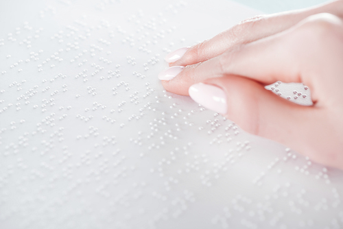close up view of young woman reading braille text on white paper