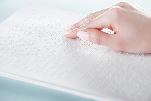 close up view of young woman reading braille text on white paper