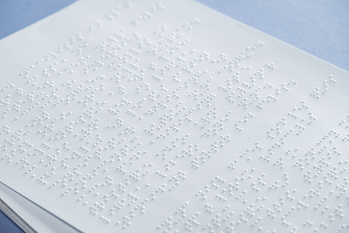 text in international braille code on white paper isolated on violet