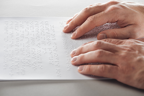 cropped view of man reading braille text with hands