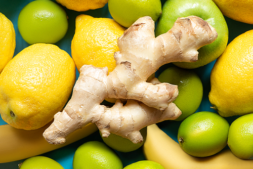 top view of ginger root on yellow lemons, bananas, green apples and limes