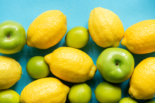 top view of ripe yellow lemons and green apples and limes on blue background