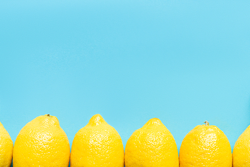 top view of ripe yellow lemon on blue background with copy space