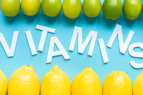 top view of ripe yellow lemons and limes on blue background with word vitamins