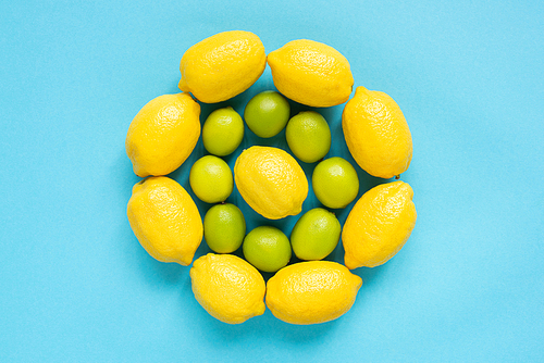 top view of ripe yellow lemons and limes arranged in circles on blue background