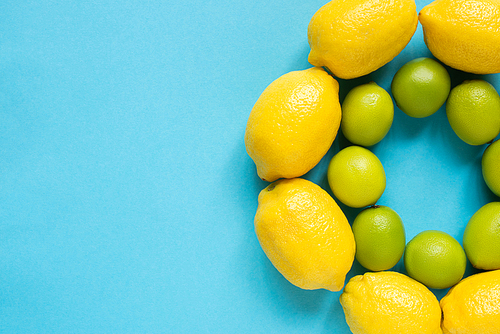 top view of ripe yellow lemons and limes arranged in circles on blue background