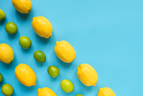 flat lay with ripe yellow lemons, green limes on blue background