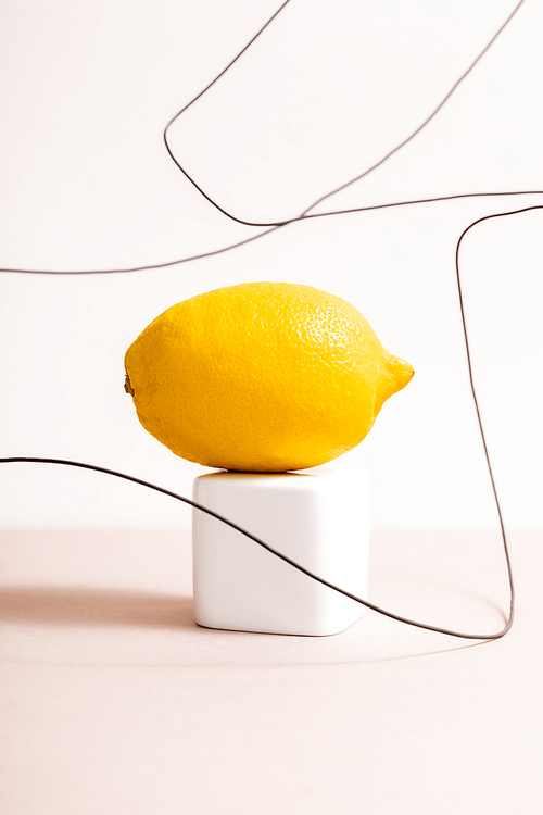 lemon on cube and wire isolated on beige