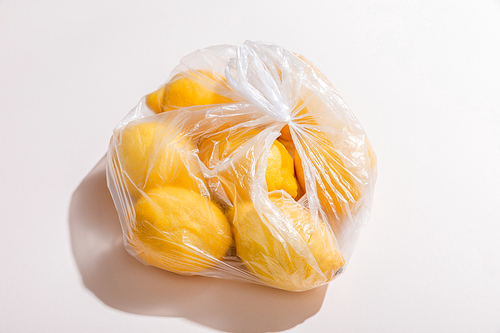fresh yellow lemons in plastic bag on grey table