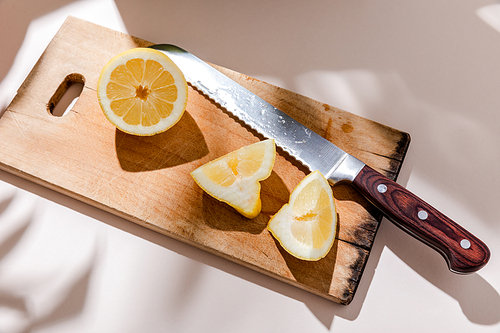 sliced lemon on wooden board on grey table with shadows