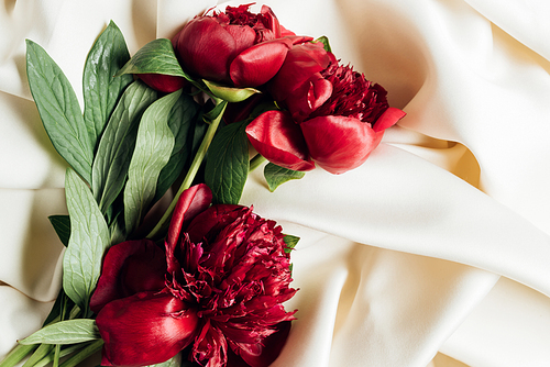 top view of bouquet of red peonies on white cloth