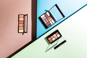 top view of eye shadow palettes on blue, green and pink