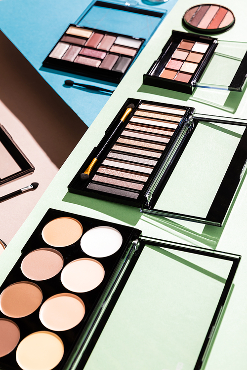 selective focus of eye shadow and blush palettes on green, blue and pink