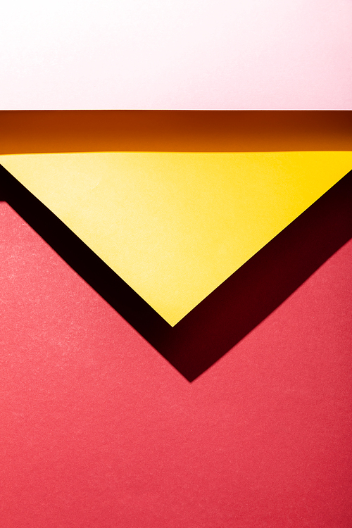 top view of empty pink and yellow paper sheets on crimson