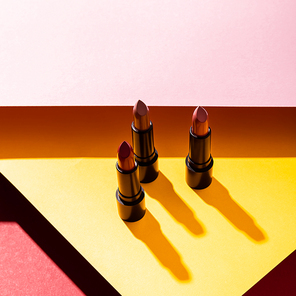 close up of lipsticks on yellow, crimson and pink