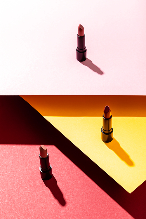 shadows near lipsticks on crimson, yellow and pink
