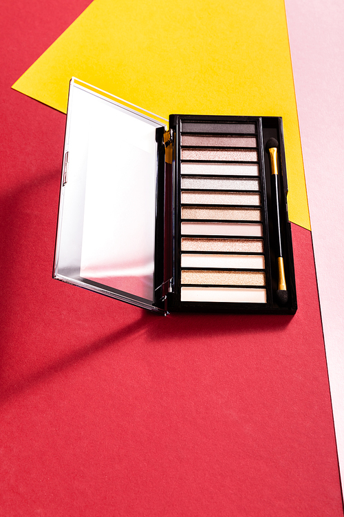 eye shadow palette and double-sided eyeshadow applicator on crimson, pink and yellow