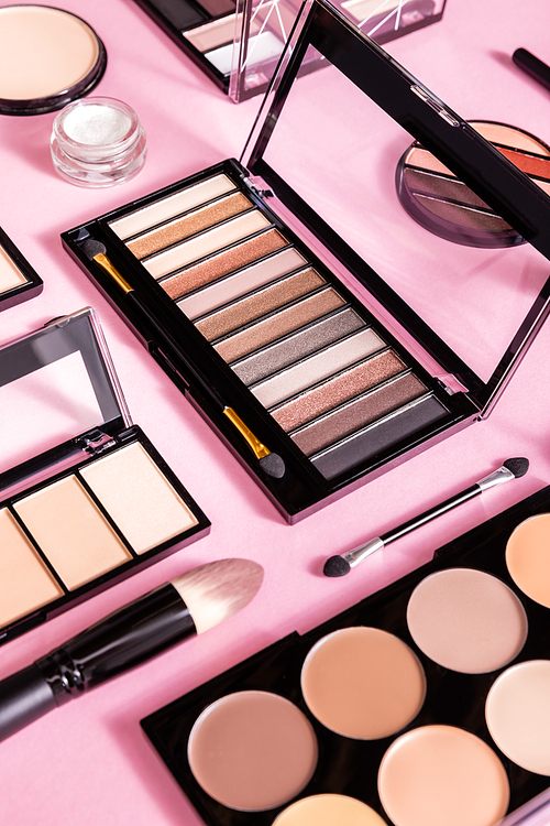eye shadow and blush palettes near cosmetic brushes and face powder on pink