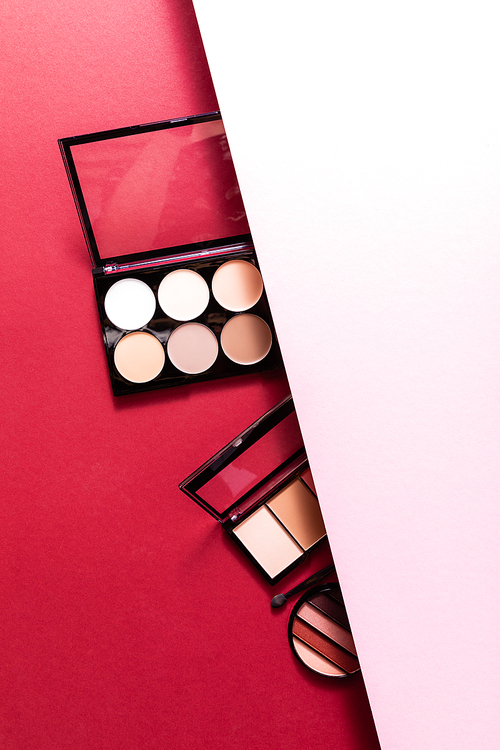 top view of pastel eye shadow and blush palettes on pink and crimson
