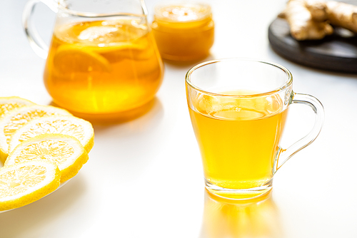 selective focus of hot tea in glass cup with lemon slices on white background