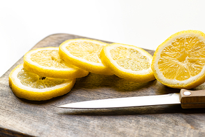 selective focus of hot lemon on wooden cutting board with knife on white background
