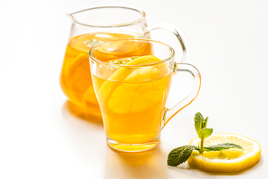 selective focus of of hot tea in glass and teapot near lemon and mint on white background