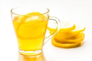 selective focus of of hot tea in glass near lemon slices on white background