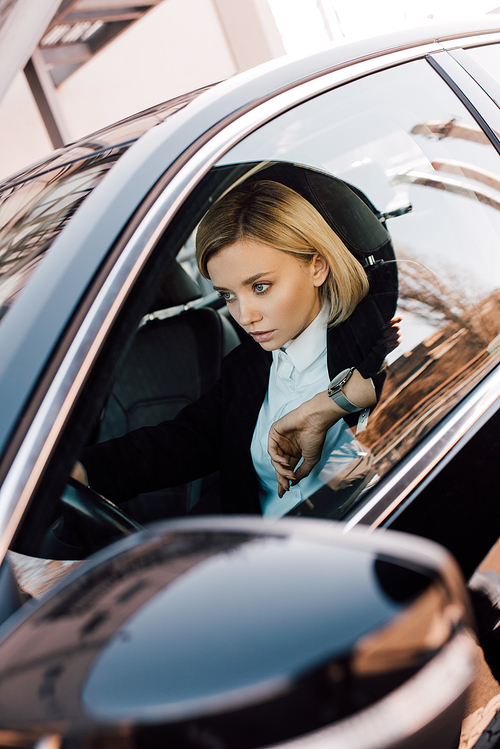 beautiful blonde woman holding steering wheel while driving car
