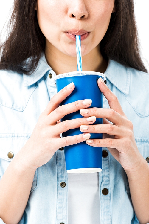 cropped view of woman in denim shirt drinking from plastic cup isolated on white